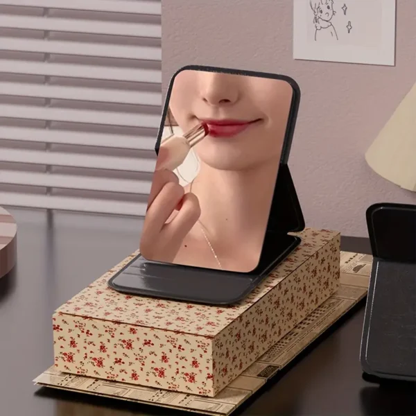 Foldable compact pocket makeup mirror with high-definition rectangular glass, faux leather frame, tabletop stand, and character-themed design